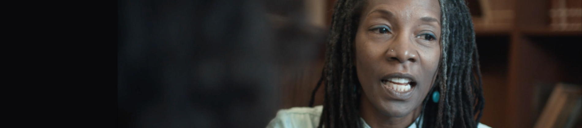 Close-up of woman speaking with bookshelves in the background.