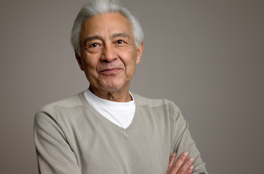 Smiling man with silver hair and arms crossed.