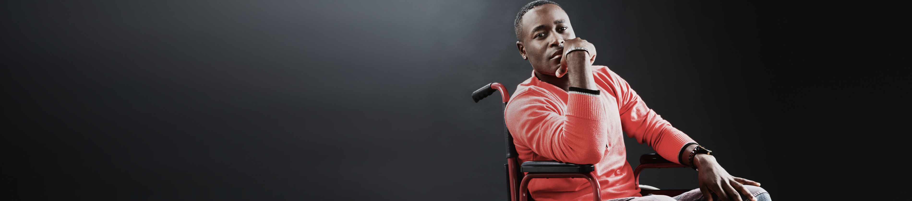 Confident man in wheelchair with hand on chin.