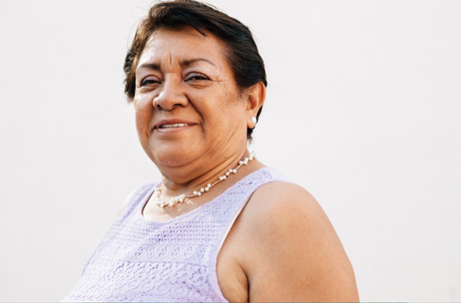 Mujer sonríe en musculosa y collar.